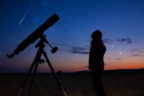 istock Man with astronomical telescope observing night sky, under the Milky way stars. 1410471676