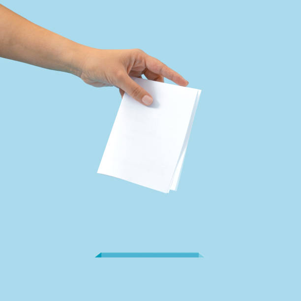 Creative concept of inserting the ballot into the box. It is your right to vote, exercise your right. Blue background. Creative concept of inserting the ballot into the box. It is your right to vote, exercise your right. Blue background. voting ballot box voting ballot polling place stock pictures, royalty-free photos & images