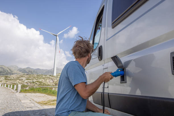 Man plugs an electric camper van to be recharged