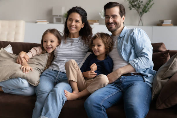 istock Family sitting on sofa at home smiling looking into distance 1410485216