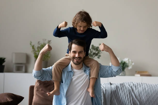 istock Little son sit on fathers shoulder demonstrate bicep strength 1410485240