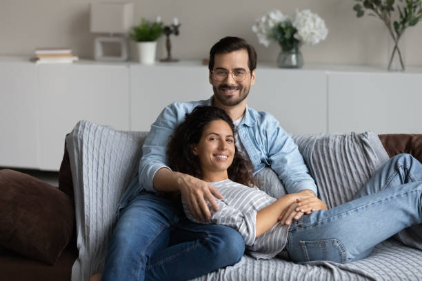 istock Couple relaxing on sofa hugging posing looking at camera 1410485589