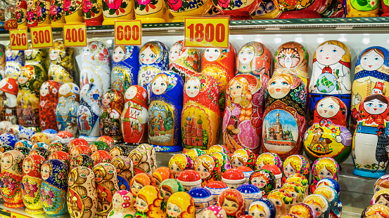 Matryoshkas, traditional Russian souvenirs for tourists. Wooden nesting dolls for sale on a shelf with a price tag, in a souvenir shop.  Selective focus.