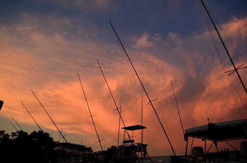 Fiery clouds at Sunset with Silhouettes of Fishing Boats docked at Sportsman Marina in Orange Beach, Alabama