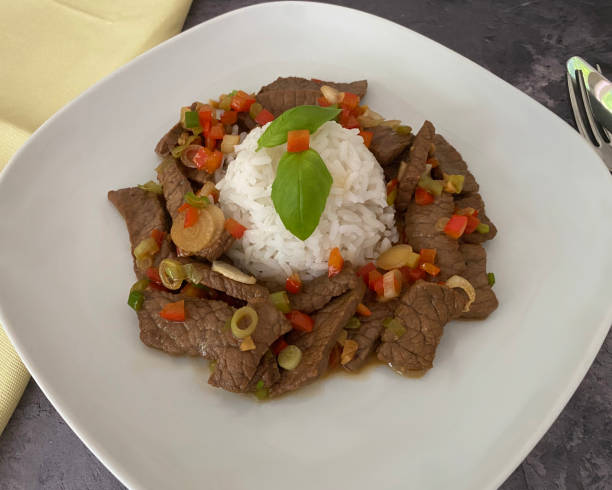 istock Stir fry, marinated, fried strips of beef with chili pepper, basil and spring onions, served with rice. 1410491995