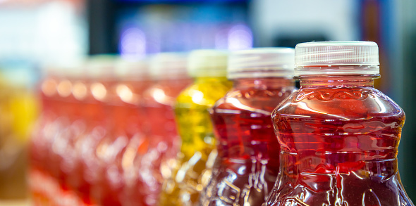 A row of brightly colored bottles of juice for sale on the shelf of a convenience store.
