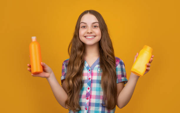 istock smiling child with shampoo bottle on yellow background 1410494756