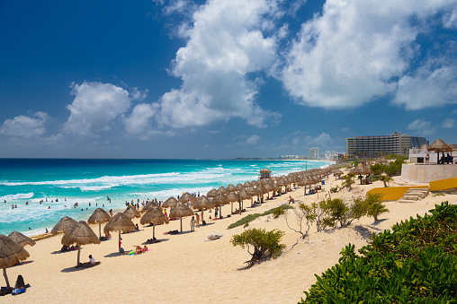 Umbrelas on a sandy beach with azure water on a sunny day near Cancun, Mexico.