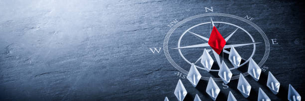 Business Leadership Concept Red Paper Boat On Compass Leading A Fleet Of Small White Boats - Business Leadership Concept overseeing stock pictures, royalty-free photos & images