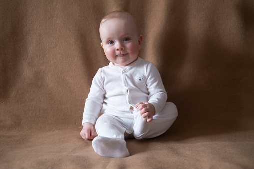 happy caucasian nine months old baby girl looking at camera during home photoshoot
