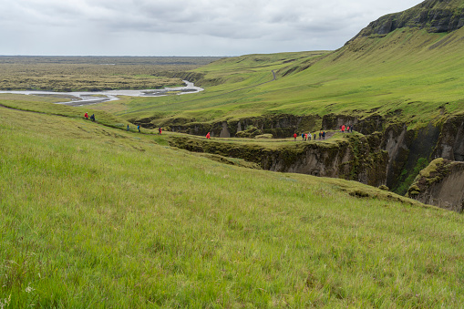 Incidental people at the Fjaðrárgljúfur Canyon with Fjadra river, 2 km long and 100m deep canyon in South East of Iceland.