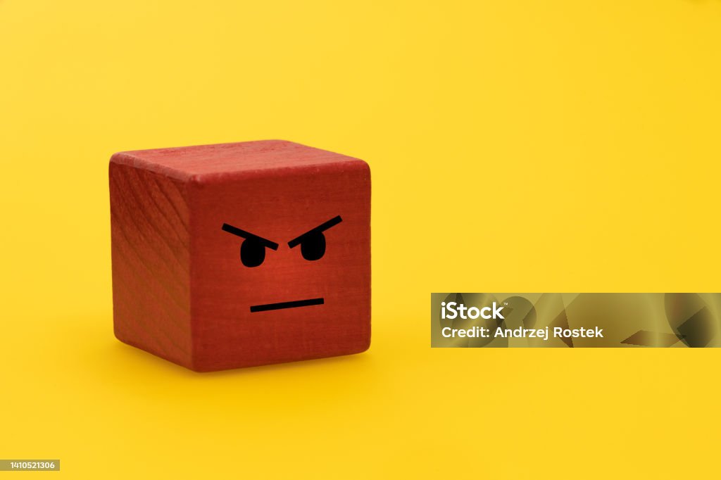 Anger and frustration, Creative concept, Outbursts of anger, therapy helping to deal with negative emotions, Red wooden block with painted human feelings, Yellow background, empty space Rudeness Stock Photo