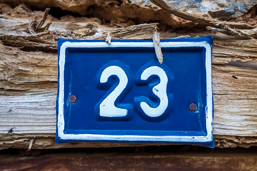 Metal 23 sign on old wooden door