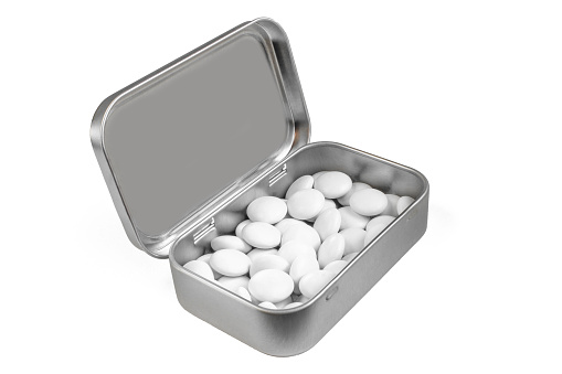 White dragee in elegant metal box. Shiny silver candy tin isolated on white background