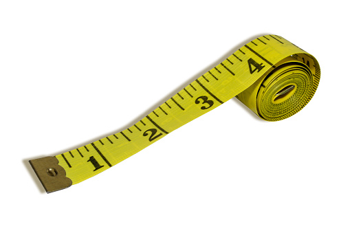 Rolled measuring tape isolated on white background. Yellow inches imperial measurement system