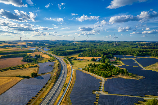 solar farm and wind turbines near the highway road interchange (aerial)
