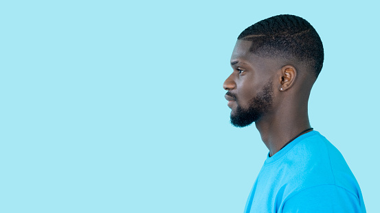 Man profile portrait. Confident look. Panoramic banner. Side view of young attractive guy face isolated on blue empty space header background.