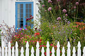 istock Quaint cottage garden with vintage white picket fence 1410540631