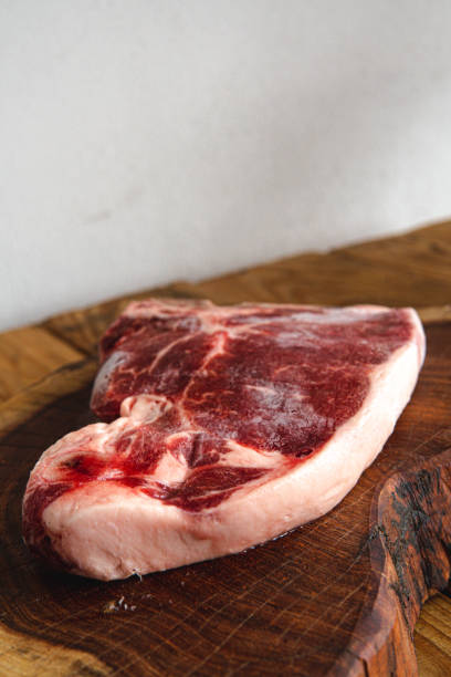 a thick cut of meat on a cut wooden log with a white background. - scotch steak imagens e fotografias de stock