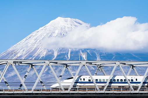 Japan - February 1, 2019 : High Speed Bullet Train Shinkansen running on railway bridge across Fuji river with Fuji mountain background in winter, Fuji city, Shizuoka