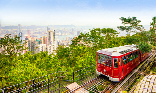 Hong Kong - December 11, 2019 : Local Tram running on the railroad up to Victoria Peak Station with Skyscraper Buildings of Hong Kong