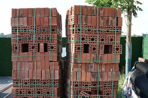 pallets and packages of freshly produced red bricks in a construction warehouse on the street. Concept of repair and building materials