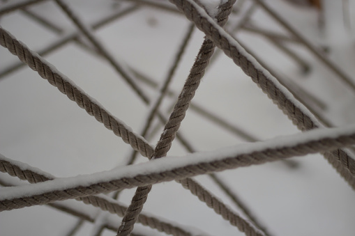 Tangled ropes. Crossing ropes. Texture of thread in snow. Labyrinth of ropes. Details of playground.