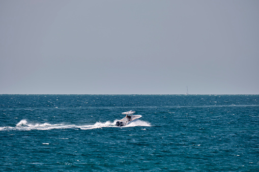 Seascape with ripple surface of blue sea water with white speedboat swimming fast on calm waves.