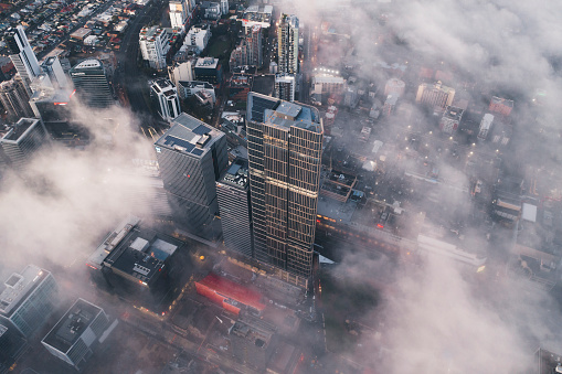 Aerial view of a downtown central business district with fog and mist amongst buildings in the morning sun