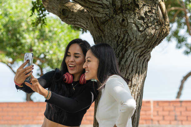 istock Friends having fun while taking selfies in a park 1410556772