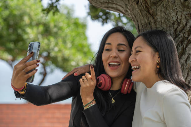 Two happy friends embraced while taking a selfie in a park