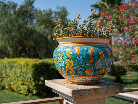 Typical sicilian Ceramic Pot sitting on a coloumn pedestal in a garden during sunrise