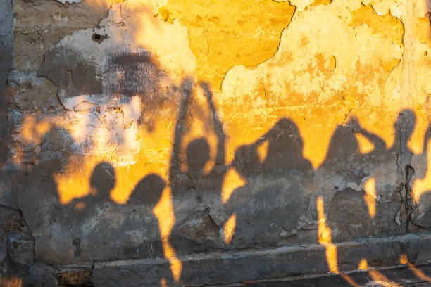 istock Shadows of dancing people on an old stone wall at sunset time. 1410567214