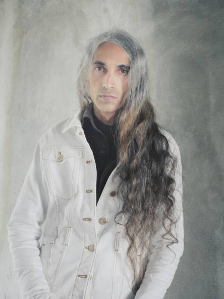 istock Long haired man in white denim jacket looking at camera 1410568222