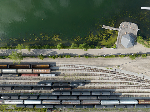 A directly overhead, aerial view looking down on cargo, freight train cars in Hamilton, ON, Canada at the waterfront railway yard, pictured during the day.