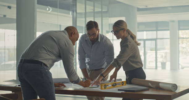 istock Focused creative architects drawing and brainstorming their next project together. Designers working on construction plan. Group of business people brainstorming and planning with paperwork at work. 1410570709