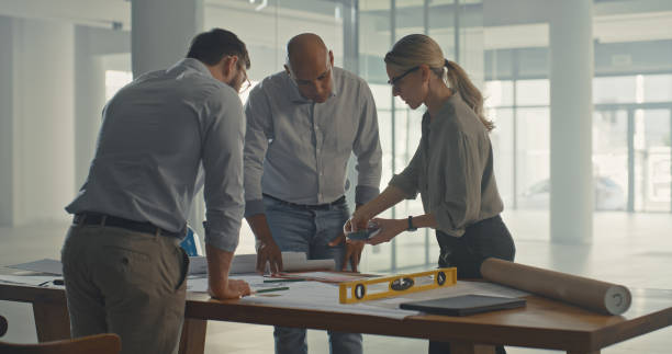 istock Architects drafting blueprint plans for a construction project. Team of ambitious designers and engineers developing a layout and assessing building plans for commercial property development 1410570957