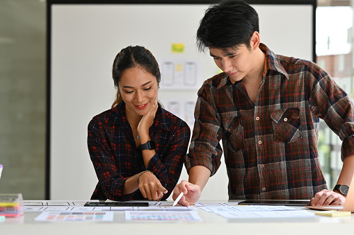 Young Creative Asian woman and man Ux Ui designer planning to create smartphone application.
Website design, app development template, wireframe design concept.