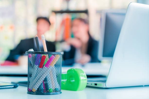 Blurred office workers working in background with office desk and laptop in the front for abstract background.