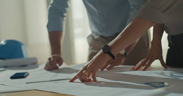 istock Two architects discussing a blueprint in an office. Hands of engineers talking floor plans and architectural plans during a meeting. Partners working on a strategy for a building construction project 1410575056