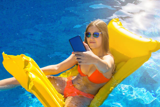istock Young girl using cell phone to take selfie, she is enjoying summer. 1410582793