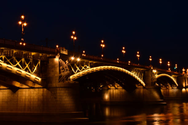 the Margaret bridge in Budapest. perspective view at night. brightly illuminated steel arches. reflection on the water. tourism and travel concept. transportation and structural design. night photo.