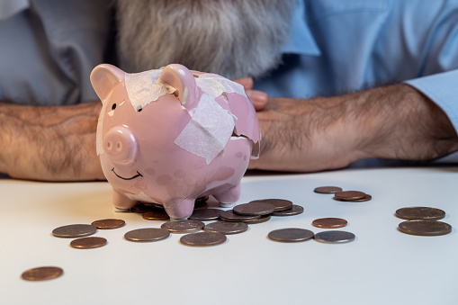 Senior businessman repairing broken piggy bank