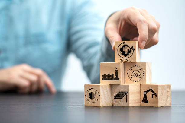 istock Businessman hand arranging wood block with net zero icon , Net zero by 2050 Carbon neutral energy or Net Zero greenhouse gas emission target on wooden cubes background 1410585369