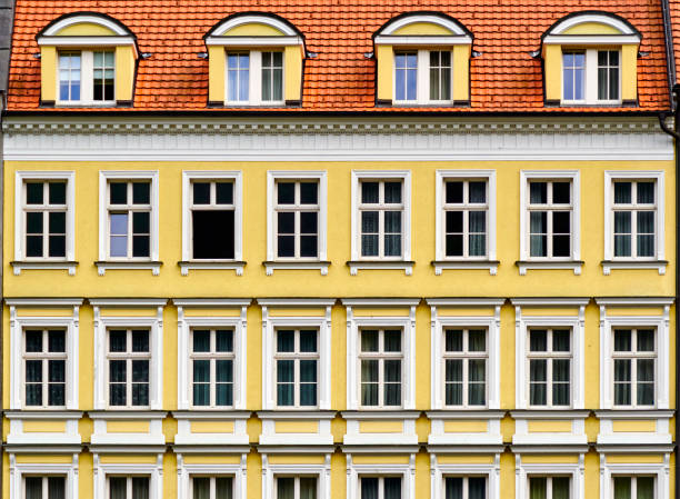 Geometrically strict yellow facade with uniformly arranged windows under a red tiled roof in Karlovy Vary, Czech Republic