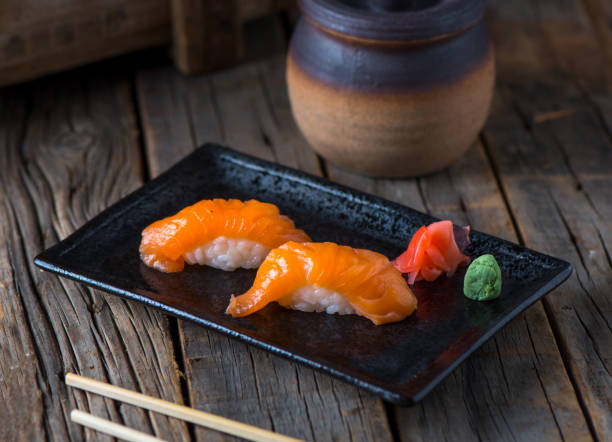 lachs authentische nigiri serviert in einer schale, isoliert auf hölzernen hintergrund seitenansicht von authentischen nigiri - sake nigiri stock-fotos und bilder