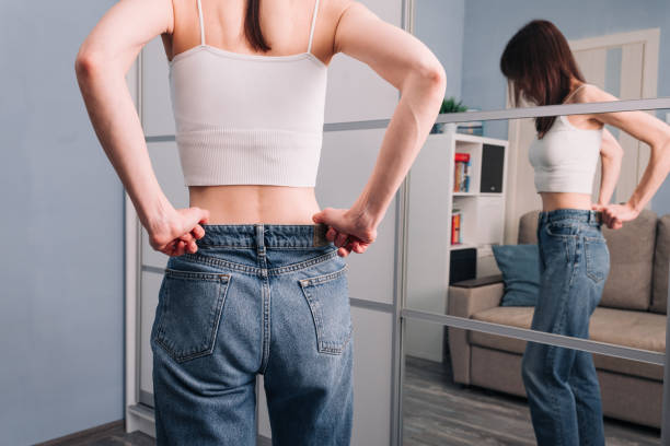 istock Woman put jeans and showing weight loss. 1410588708