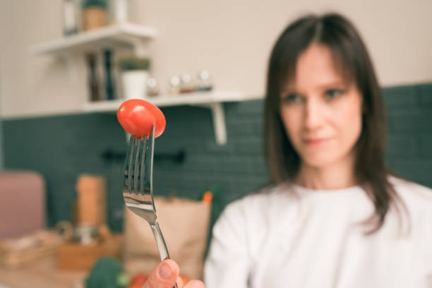 istock Young woman try fun eating fresh cherry tomato at home kitchen 1410588871