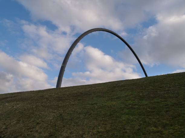 metallic arch formed from pipe of the hoheward halde horizon observatory in front of a dramatic cloudy sky and a green meadow - horizon observatory imagens e fotografias de stock