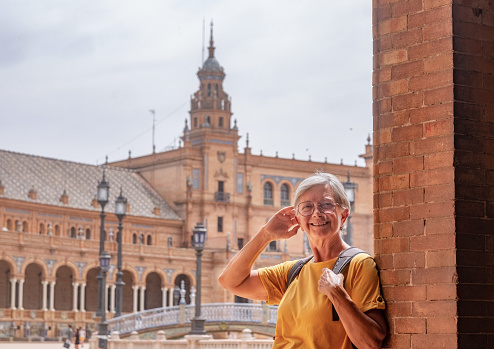 Happy senior woman traveling in Seville, Spain visiting famous places - attractive elderly traveler enjoying summer and cultural vacation
